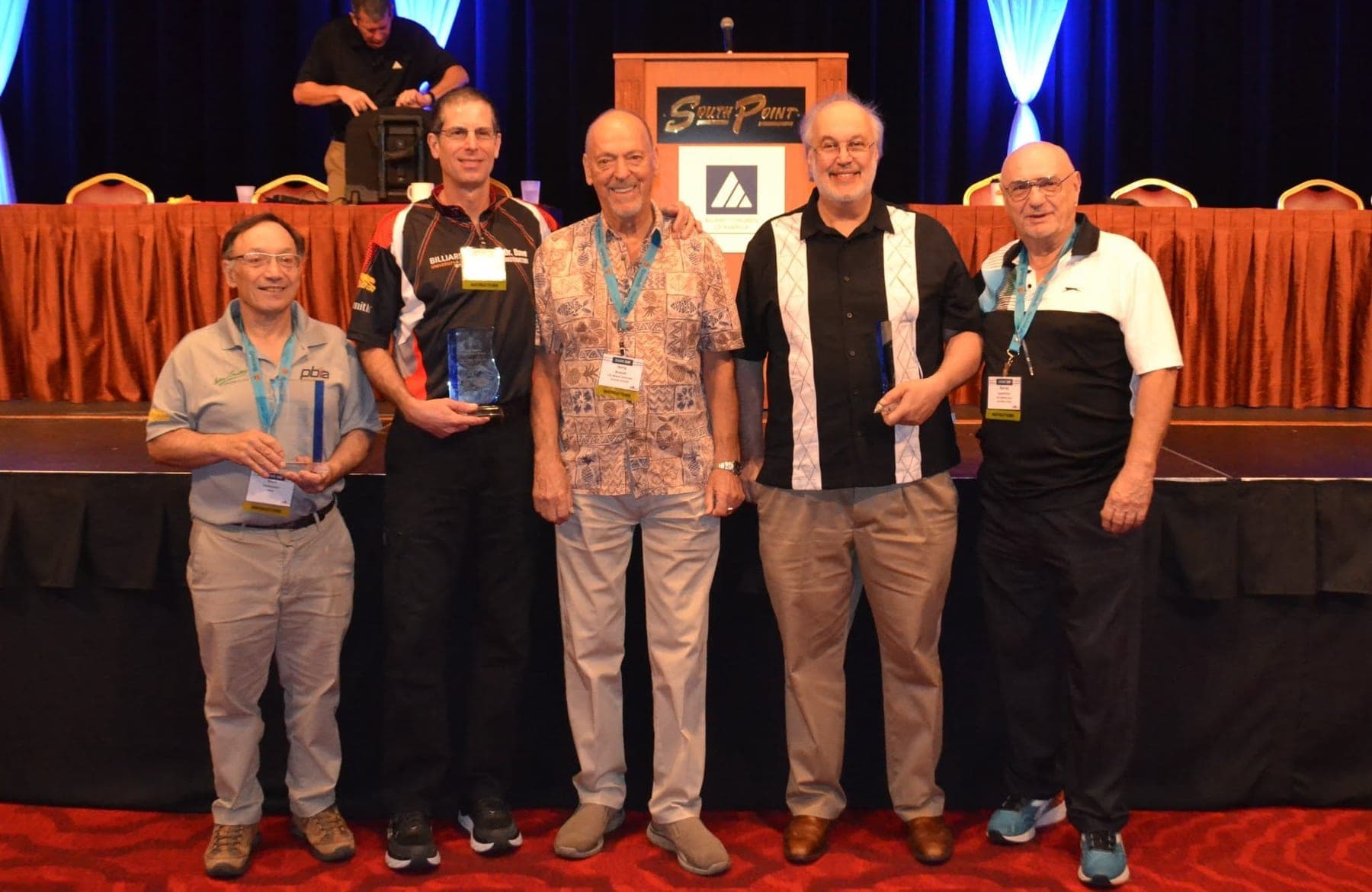 Randy Goettlicher, far right, with fellow PBIA instructors holding awards on stage at a Billiard Congress of America event.