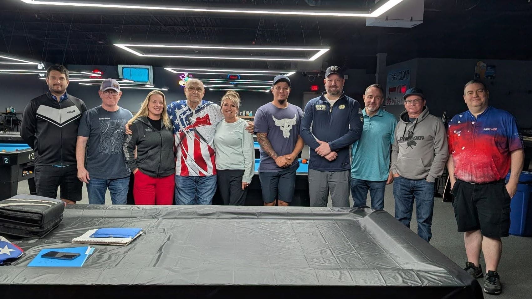 Randy Goettlicher with a group of students at one of his pool schools, standing behind a table laid out with notebooks.